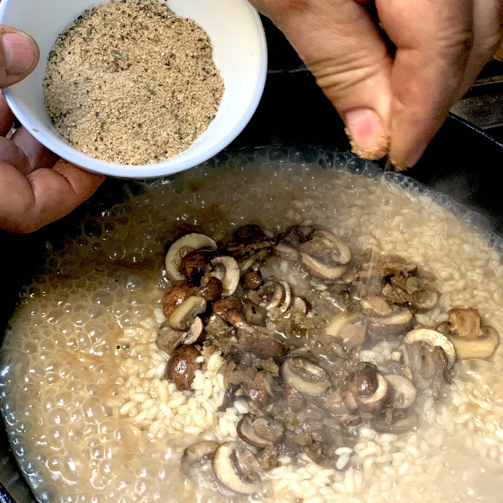 cooking risotto with mushrooms and a hand sprinkling with omnivore Porcini